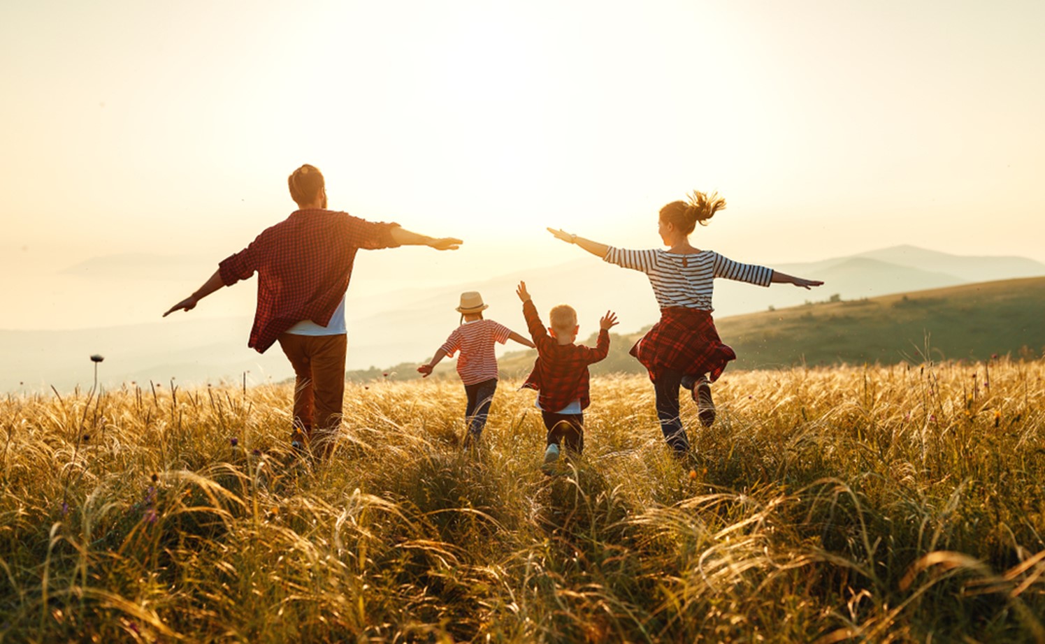 family running in a field with arms open